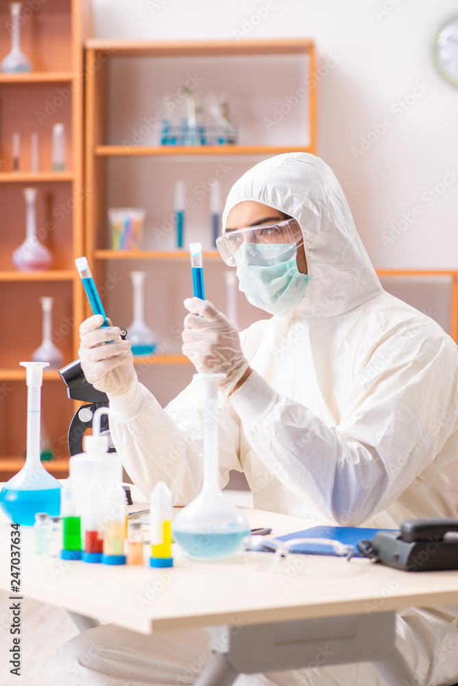 Young biochemist wearing protective suit working in the lab Young biochemist wearing protective suit working in the lab