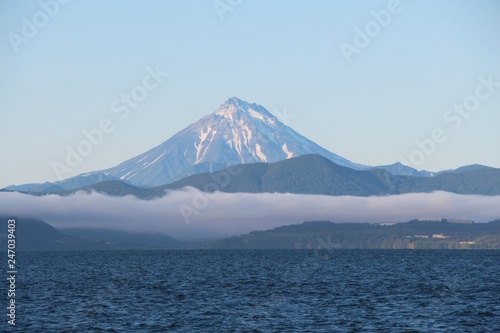 View of Vilyuchinsky volcano  also called Vilyuchik  from tourist boat. The cloud lies on the coastal cliffs. Vilyuchinsky is a stratovolcano in the southern part of Kamchatka Peninsula  Russia.