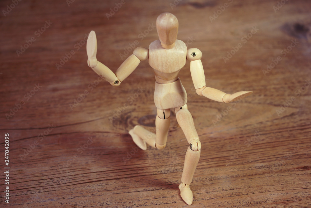 Wooden model showing dramatical pose on darker wooden table background Wooden model showing dramatical pose on darker wooden table background