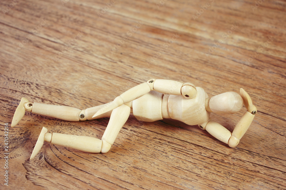 Wooden model showing dramatical pose on darker wooden table background Wooden model showing dramatical pose on darker wooden table background