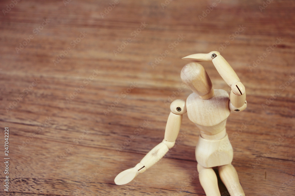 Wooden model showing dramatical pose on darker wooden table background Wooden model showing dramatical pose on darker wooden table background