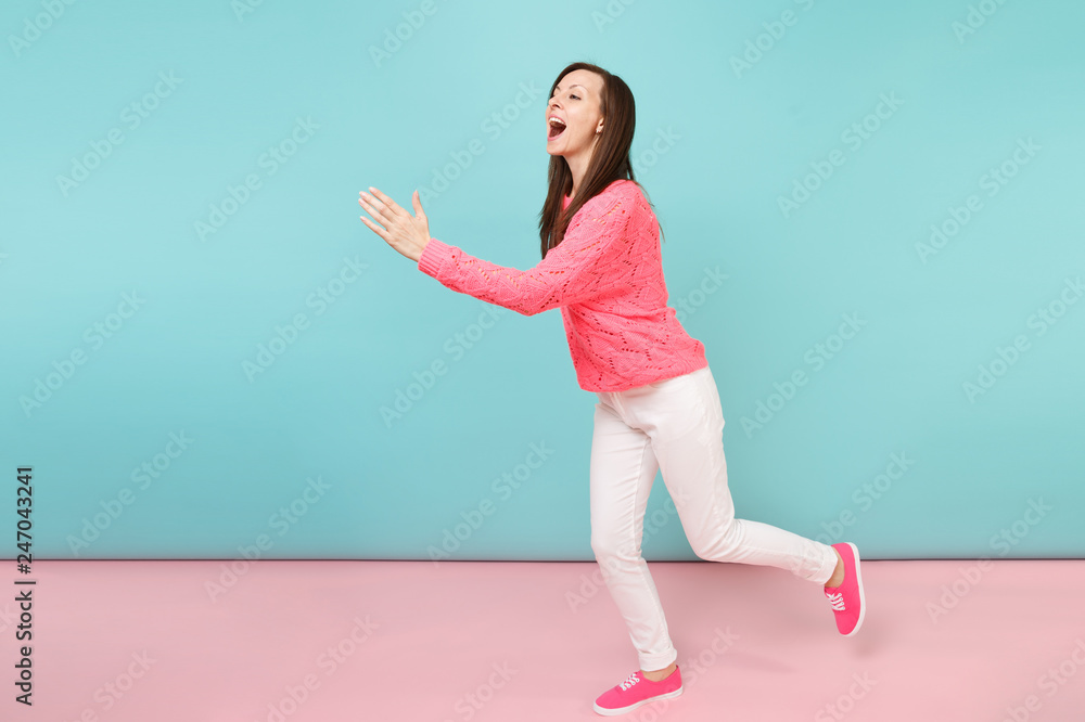 Full length portrait of smiling young woman in knitted rose sweater, white pants posing isolated on bright pink blue pastel wall background in studio. Fashion lifestyle concept. Mock up copy space. Full length portrait of smiling young woman in knitted rose sweater, white pants posing isolated on bright pink blue pastel wall background in studio. Fashion lifestyle concept. Mock up copy space.