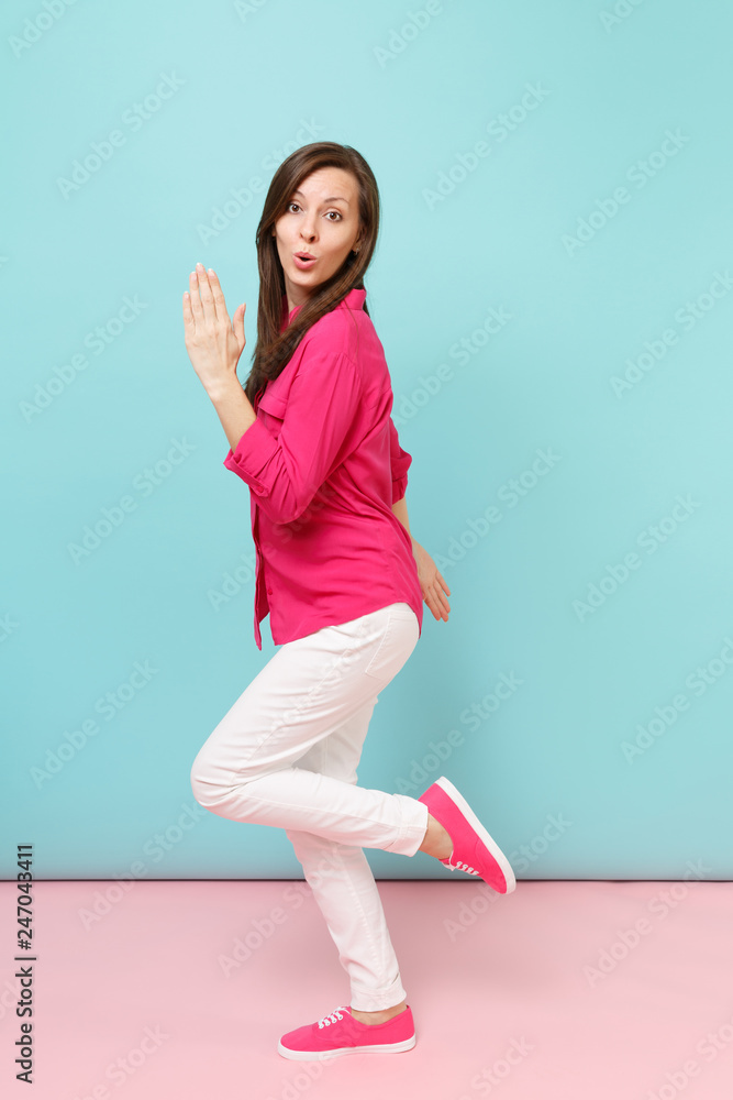 Full length portrait of smiling young pretty woman in rose shirt blouse, white pants posing isolated on bright pink blue pastel wall background studio. Fashion lifestyle concept. Mock up copy space. Full length portrait of smiling young pretty woman in rose shirt blouse, white pants posing isolated on bright pink blue pastel wall background studio. Fashion lifestyle concept. Mock up copy space.