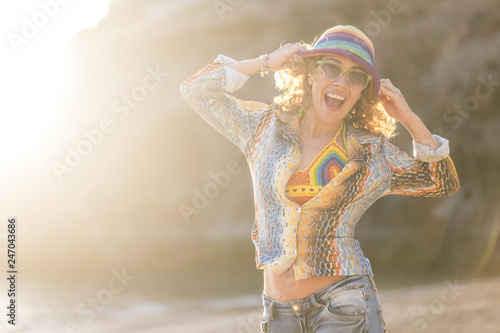Beautiful and happy young woman shout and laugh outdoor at the beach with sunny day and sunset in background - colorful and hippy style happiness for caucasian lady - cute attractive girl in holiday