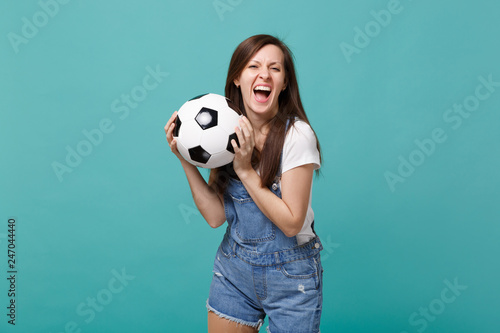 Screaming young woman football fan cheer up support favorite team with soccer ball isolated on blue turquoise background. People emotions, sport family leisure lifestyle concept. Mock up copy space. © ViDi Studio
