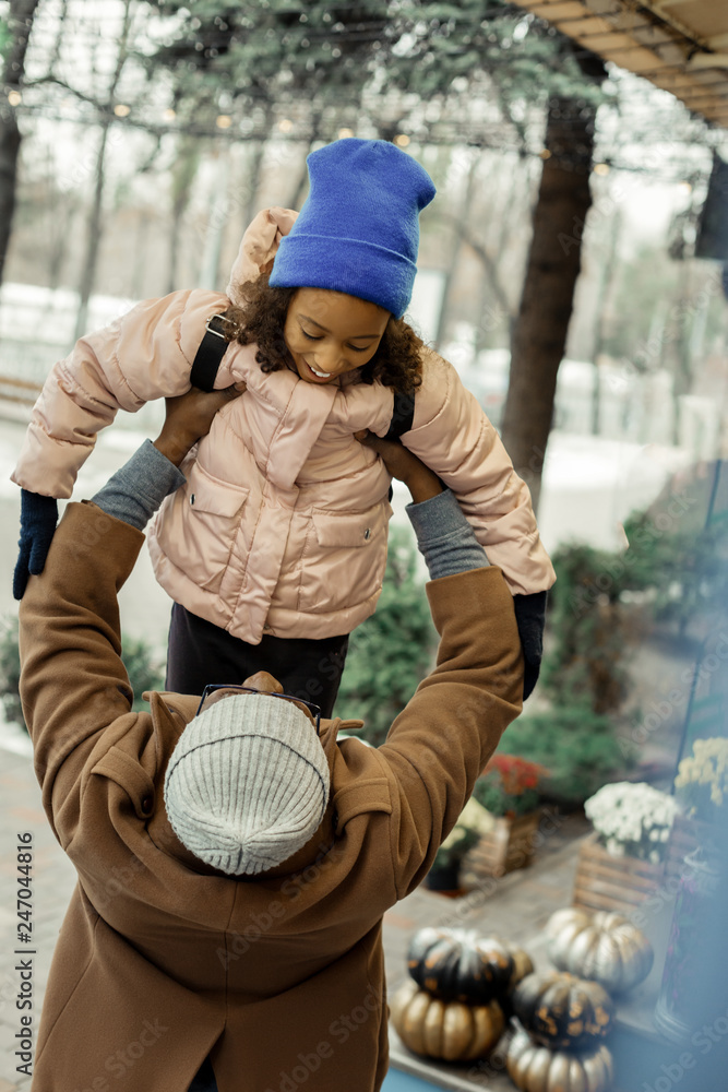 Father wearing brown coat holding his little girl on his hands Father wearing brown coat holding his little girl on his hands