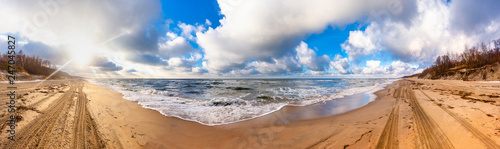 panorama of the sea coast with a sandy beach in sunny weather with clouds in the sky
