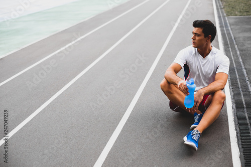 Thoughtful athlete drinking bottle of water outdoor