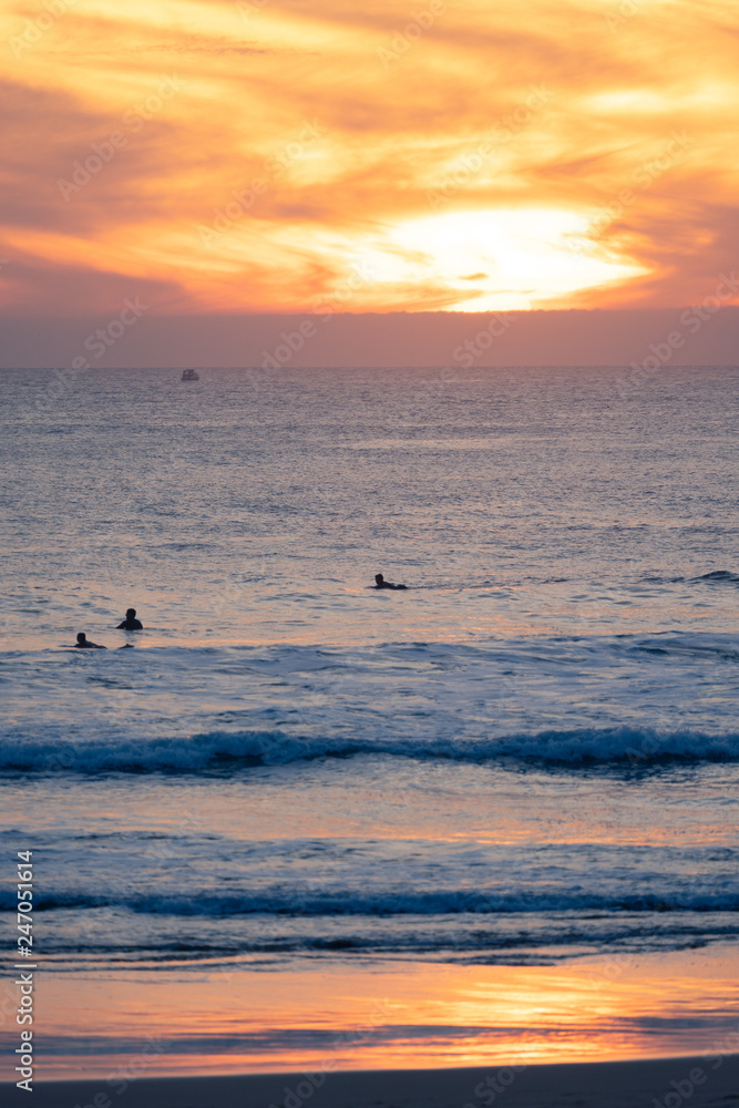 Carcavelos beach filled with many surfers at Sunset, Lisbon, Portugal