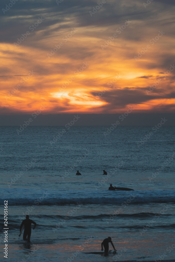 Carcavelos beach filled with many surfers at Sunset, Lisbon, Portugal