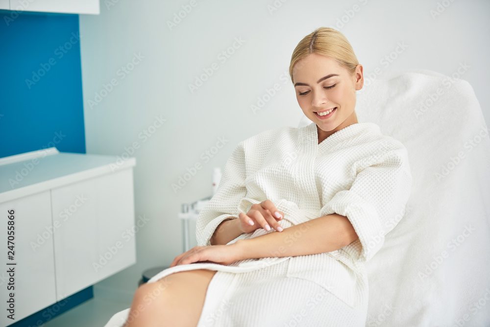 Smiling young lady enjoying results of cosmetic procedure in beauty salon Smiling young lady enjoying results of cosmetic procedure in beauty salon