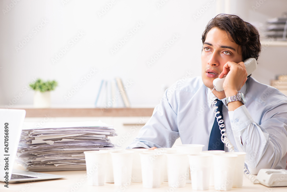 Young employee addicted to coffee Young employee addicted to coffee