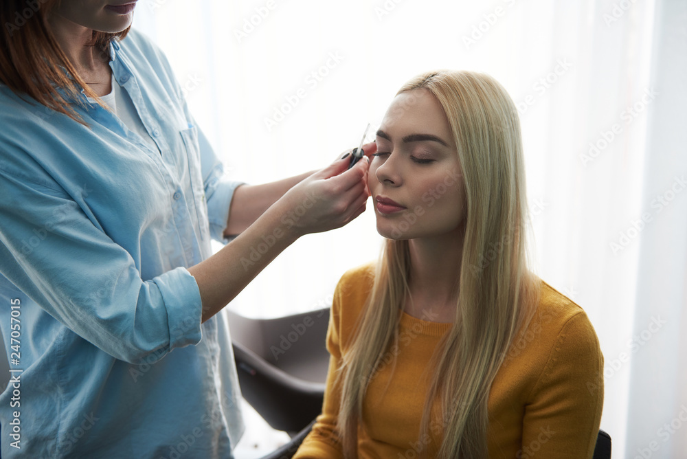 Fototapeta premium Professional makeup artist working with client in visage studio