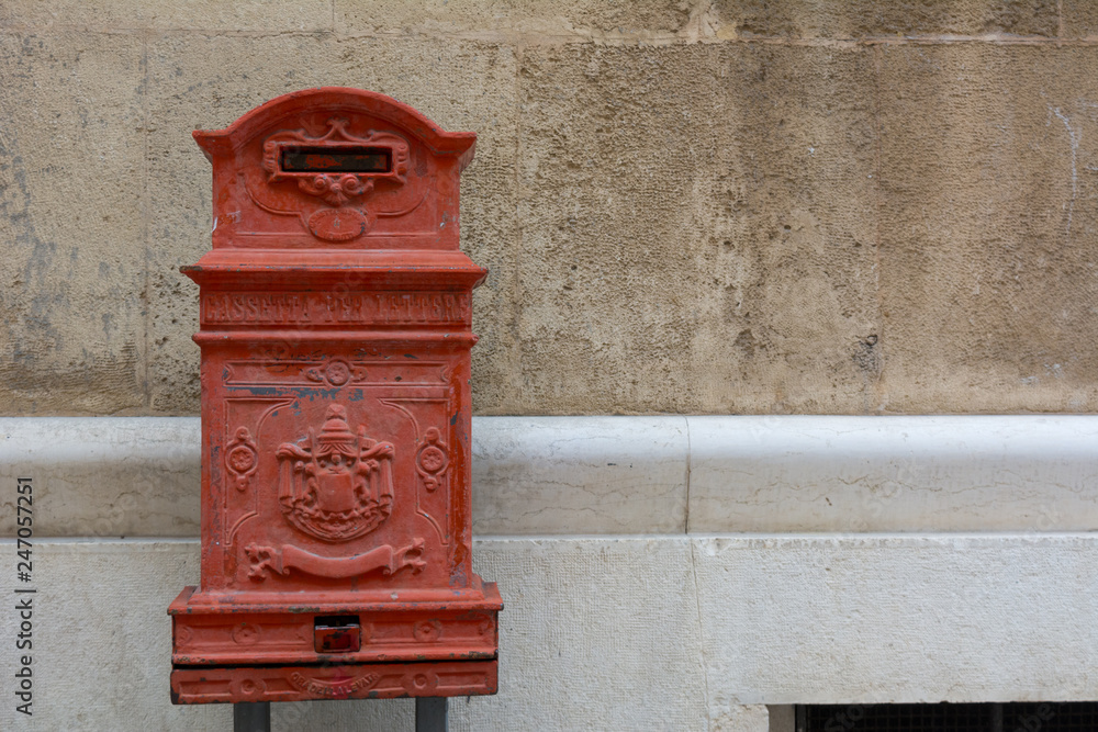 Red Ancient Letter Box in the City of Matera on Blur Background Red Ancient Letter Box in the City of Matera on Blur Background