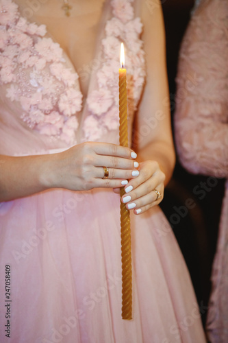A young girl holds a lit candle in the church.