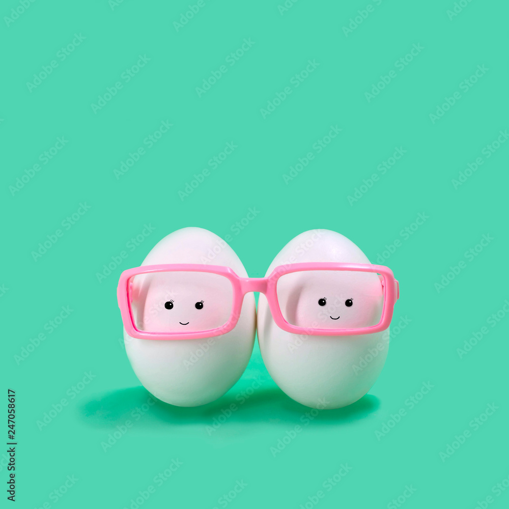 Two eggs in pink glasses like Siamese twins Two eggs in pink glasses like Siamese twins
