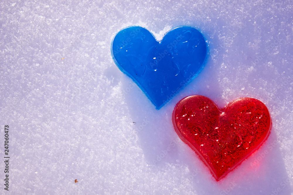 Two hearts are red and blue in the snow. Handmade soap in the shape of a heart. Love and valentines day concept. Romantic background with free space for text. Two hearts are red and blue in the snow. Handmade soap in the shape of a heart. Love and valentines day concept. Romantic background with free space for text.