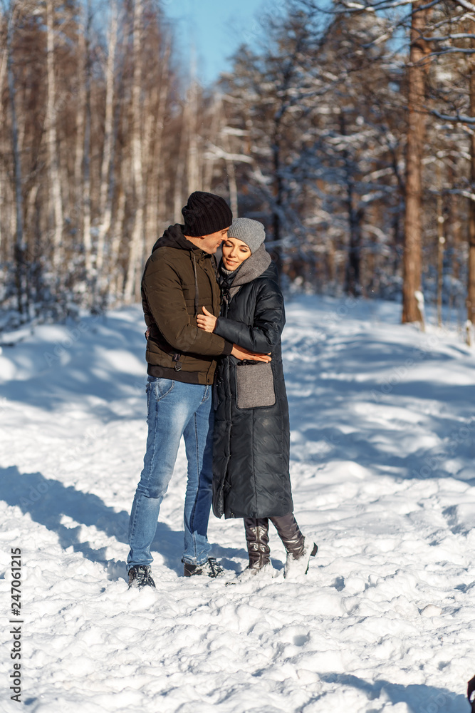 A happy couple with a dog (black Labrador) having fun outside in the forest on a sunny frosty winer day. A happy couple with a dog (black Labrador) having fun outside in the forest on a sunny frosty winer day.
