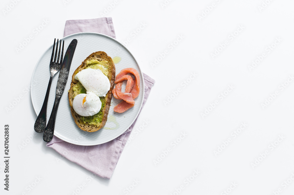 Toast with avocado, egg, salmon and black bread. Top view, white background, space for text