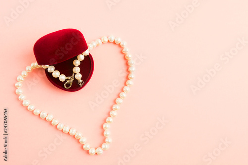 Heart of pearls necklace with opened gift box on pink background