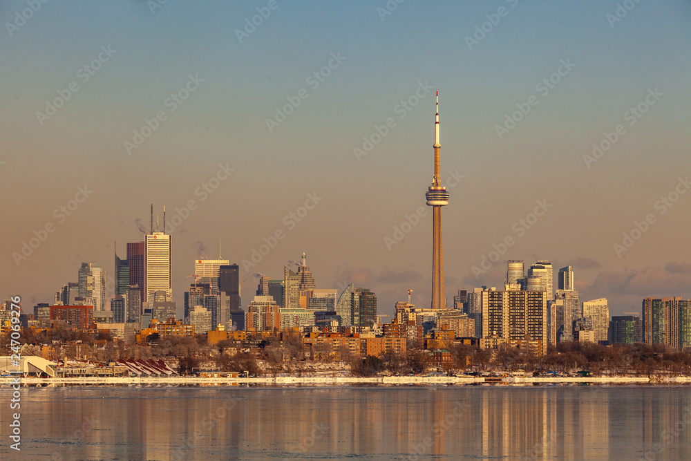 Obraz premium Toronto, CANADA - February 1th, 2019: Panoramic Canadian winter landscape near Toronto, beautiful frozen Ontario lake at sunset. Scenery with winter trees, water and blue sky.