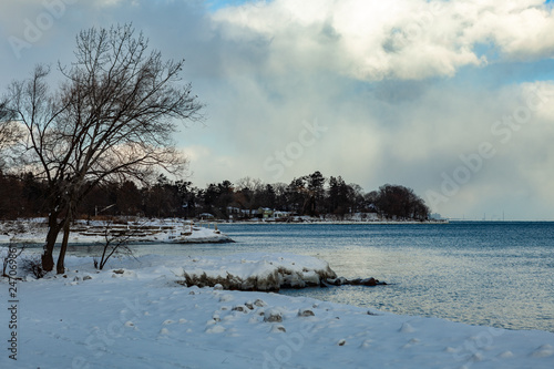 Toronto  CANADA - January 27th  2019  Panoramic Canadian winter landscape near Toronto  beautiful frozen Ontario lake at sunset. Scenery with winter trees  water and blue sky.
