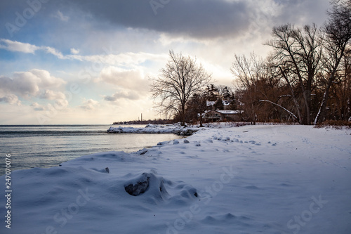 Toronto, CANADA - January 27th, 2019: Panoramic Canadian winter landscape near Toronto, beautiful frozen Ontario lake at sunset. Scenery with winter trees, water and blue sky.