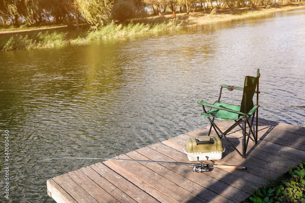 Folding chair tackle box and rod for fishing on wooden pier at
