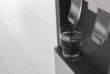 Modern water cooler with glass indoors, closeup. Space for text