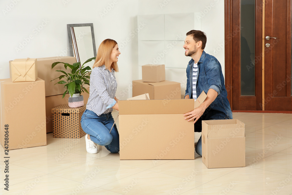 Happy couple unpacking moving box in their new house Happy couple unpacking moving box in their new house