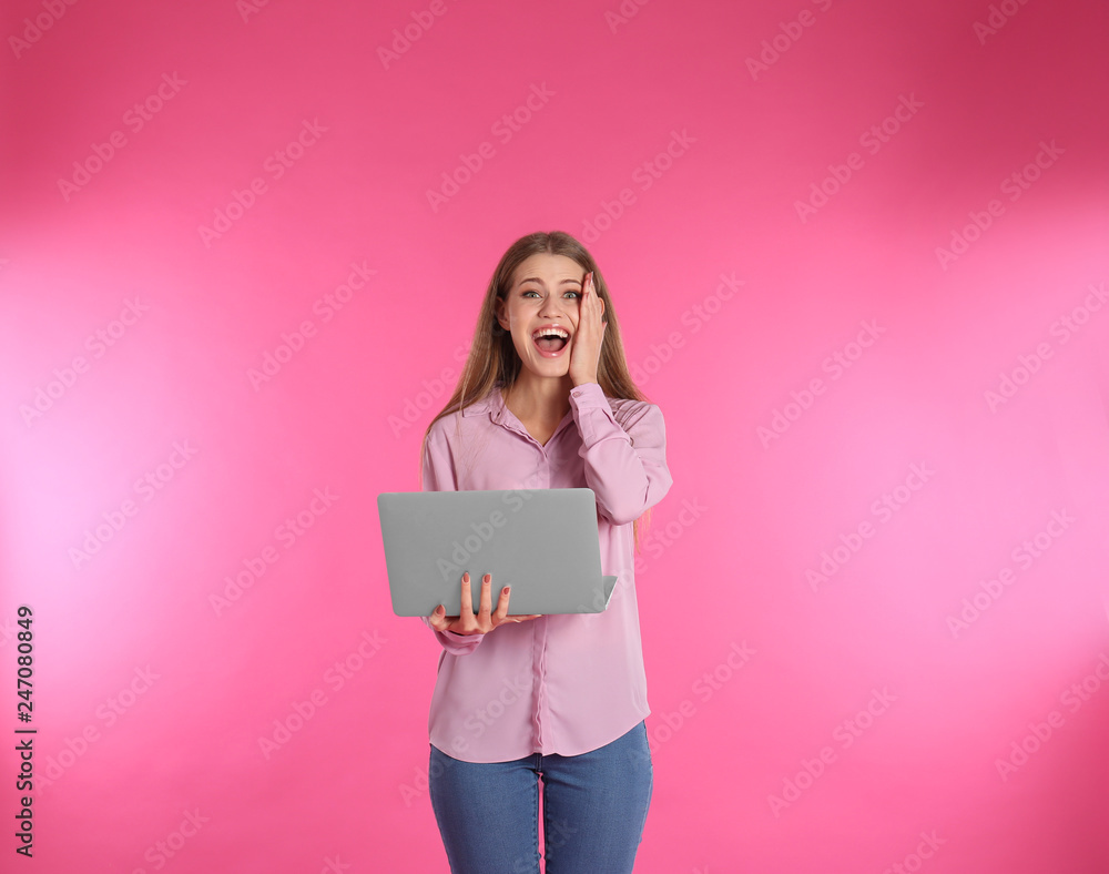 Emotional young woman with laptop celebrating victory on color background Emotional young woman with laptop celebrating victory on color background