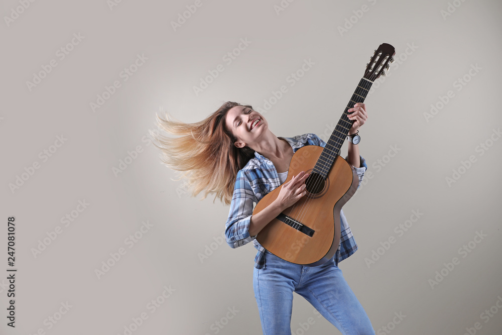 Young woman playing acoustic guitar on grey background. Space for text
