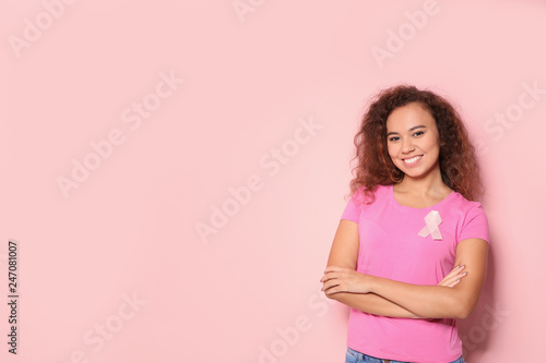 African-American woman with silk ribbon and space for text on color background. Breast cancer awareness concept