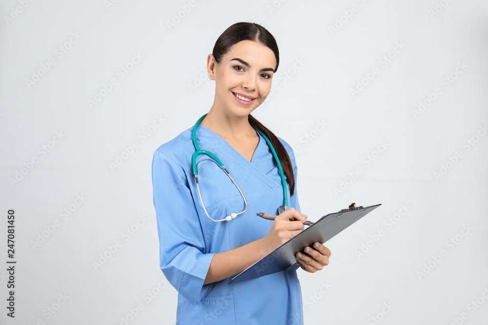 Portrait of medical assistant with stethoscope and clipboard on light background Portrait of medical assistant with stethoscope and clipboard on light background