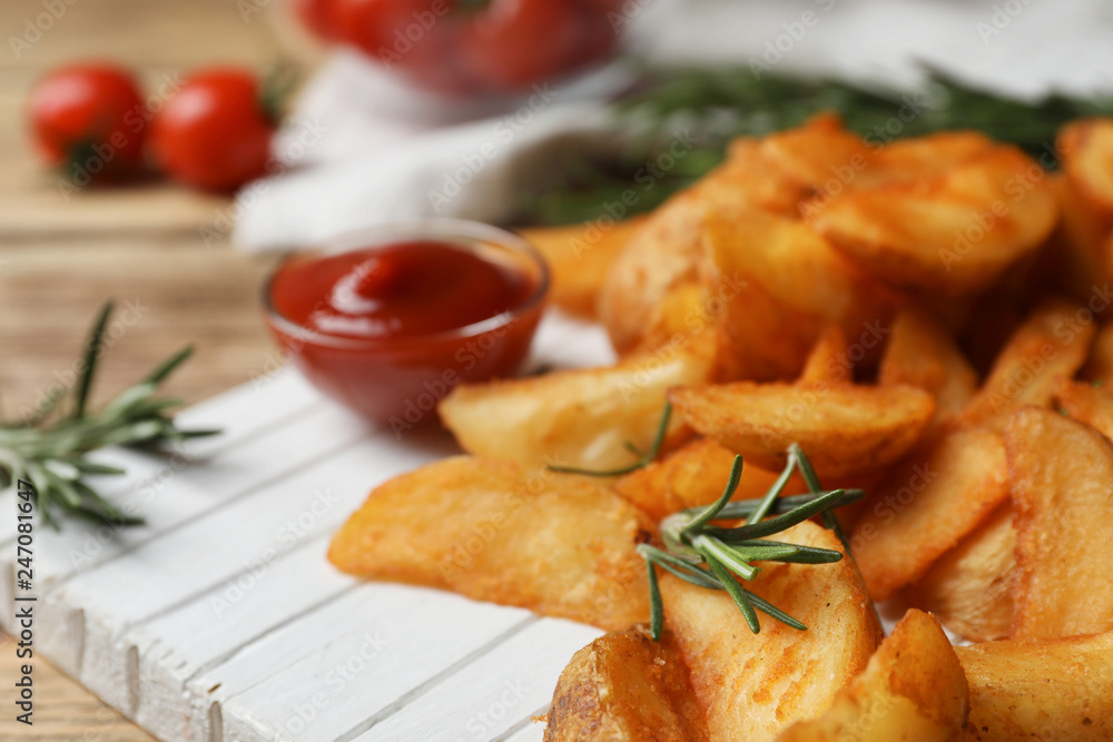 Wooden board with baked potatoes and rosemary on table, closeup Wooden board with baked potatoes and rosemary on table, closeup
