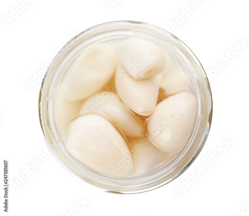 Glass jar with preserved garlic on white background, top view