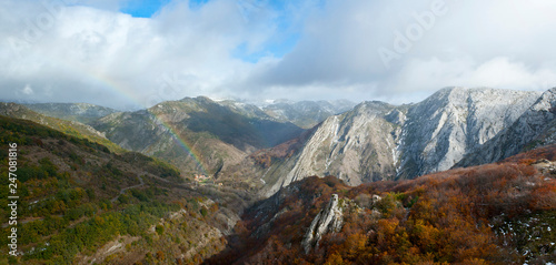Mountainous landscape with beech forests and rainbow.