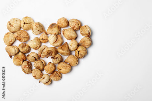 Heart shaped heap of dried figs on white background, top view with space for text. Healthy fruit