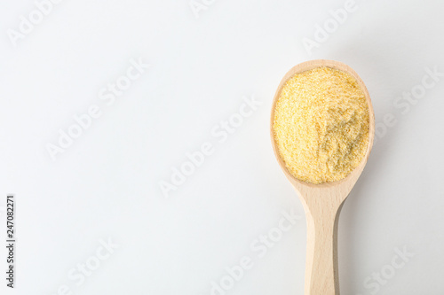 Spoon of corn flour isolated on white, top view with space for text
