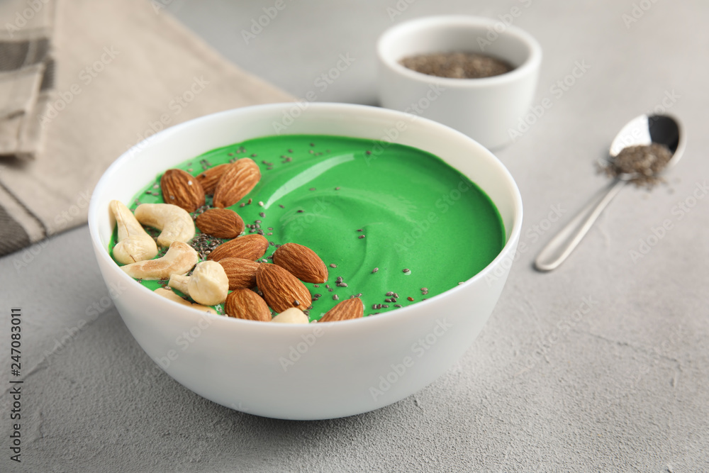 Bowl of spirulina smoothie with nuts and chia seeds on light table Bowl of spirulina smoothie with nuts and chia seeds on light table