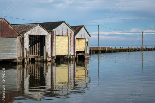 Boat houses reflected in the water.  Image taken on Lake Erie in Port Rowan, Ontario. © Lori Labrecque