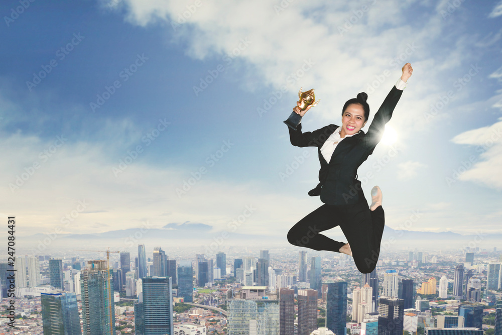 Excited businesswoman dancing with a trophy Excited businesswoman dancing with a trophy