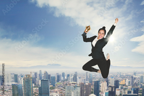 Excited businesswoman dancing with a trophy