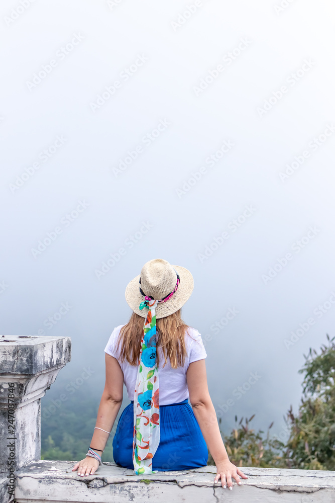 Fototapeta premium Young woman posing on the edge in the mountains with fog. Bali island, Indonesia.