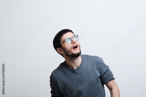 Portrait of shocked young man with glasses over white studio background