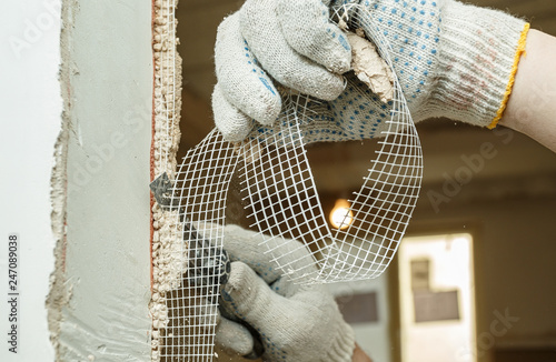 A worker is cutting off a piece of fiberglass mesh with a knife