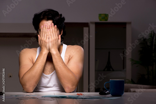 Young man calculating expences night at home  photo