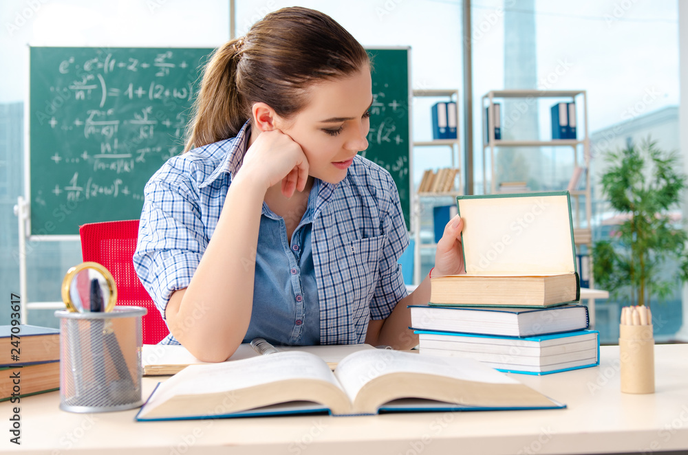 Female student with many books sitting in the classroom Female student with many books sitting in the classroom