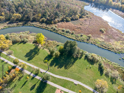 natural landscape aerial top view. city park with bushy autumnal trees, green lawns, bikeway and river