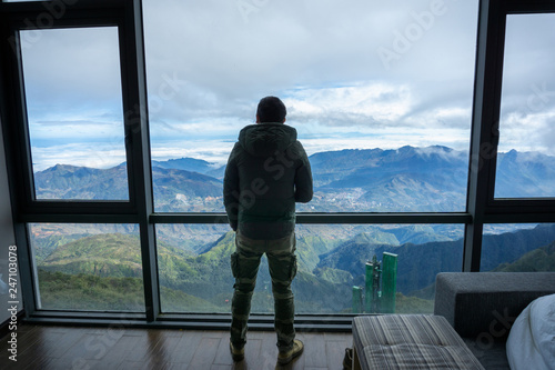 Man travelller overlooking the mountain view from hotel window